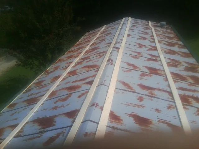 Rusted metal roof panels with new wood purlins before replacement — Storm Damage Roof Repair in Heiskell by Roofing Brothers