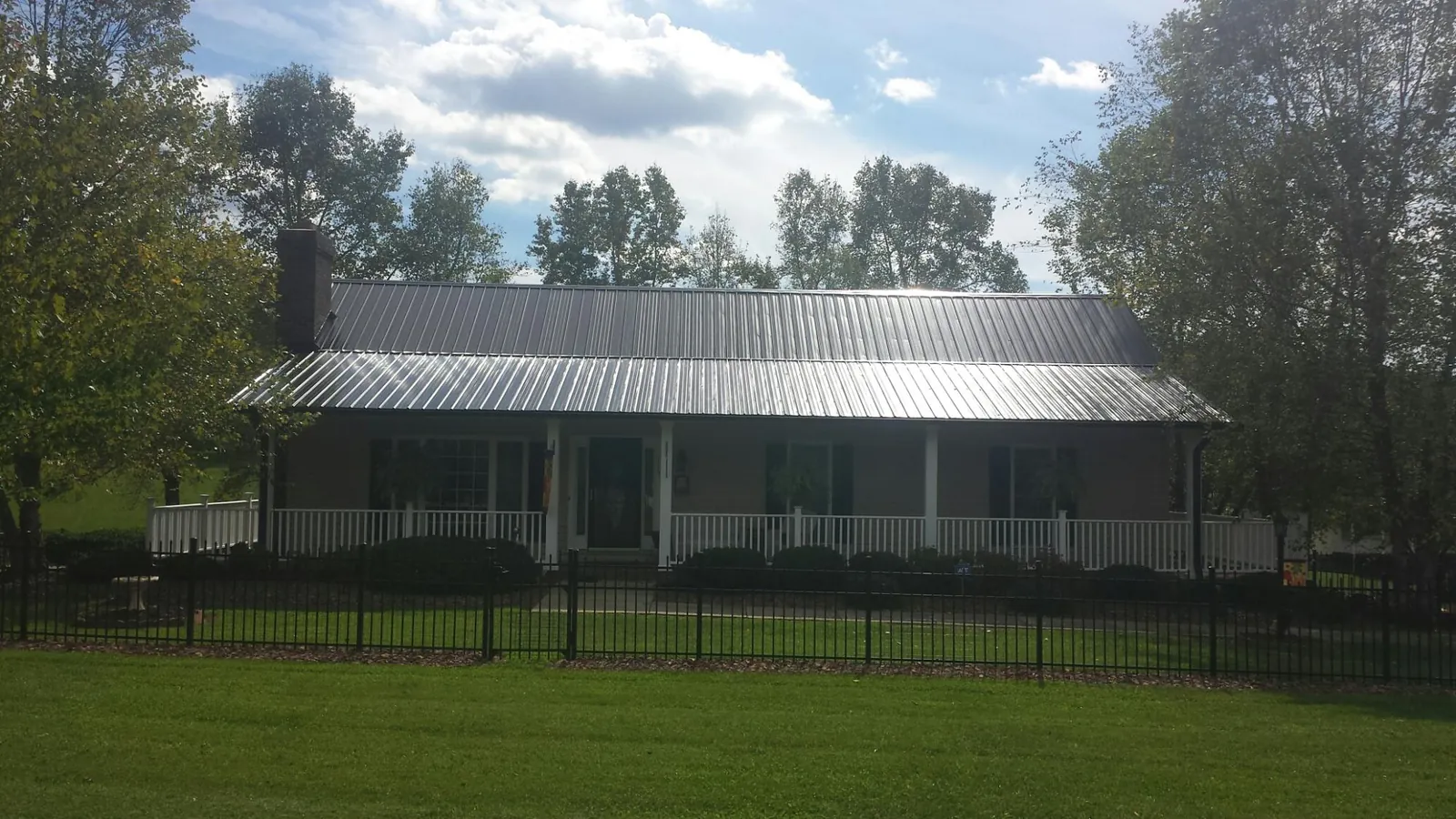Gray metal roof on a brick ranch with a full width front porch — Gutter Guard Installation work by our crew in Heiskell