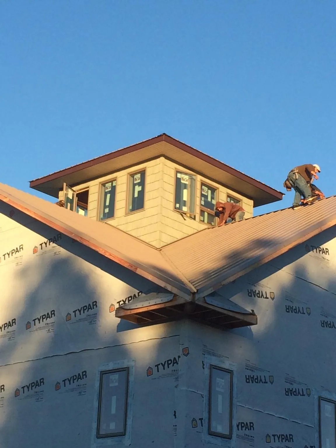 Roofers working around a rooftop cupola on a new metal roof at sunset — Roof Waterproofing in Heiskell by Roofing Brothers